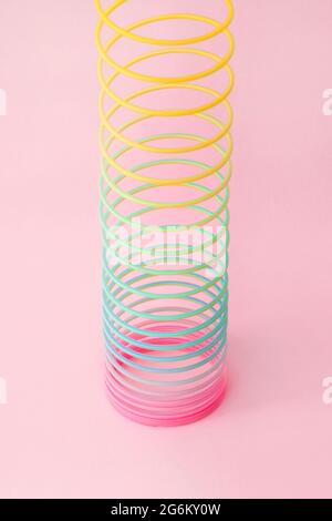 Rainbow plastic spring toy on pink background Stock Photo