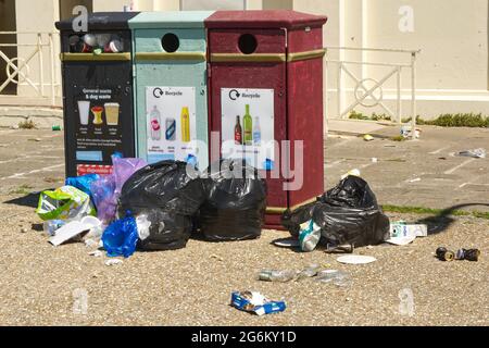 Overflowing rubbish bins with seagull damage to bags on promenade by beach at Brighton, East Sussex, England Stock Photo