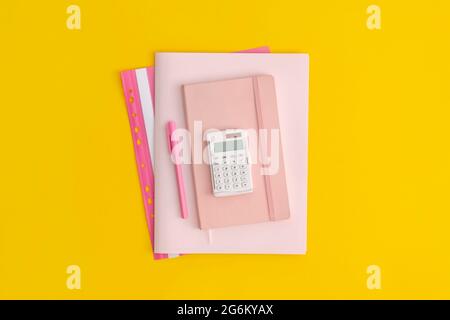 Calculator, notebook and pen on yellow background. Top view. Flat lay. Back to school concept. Stock Photo