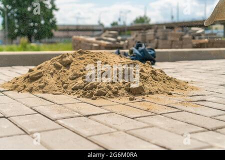 Close-up of a pile of sand lying on the new sidewalk to seal the seams between the paving slabs. Laying of paving slabs Stock Photo