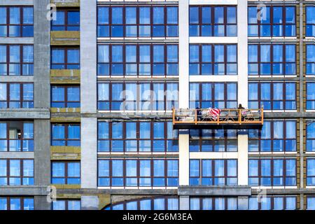 two builders in construction cradle works on a building Stock Photo