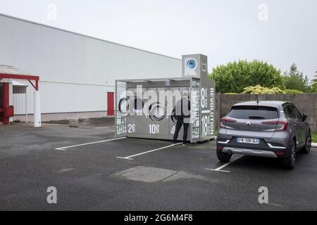 A man waiting for his laundry to finish at an outdoor laundrette in a supermarket car park in Plousgasnou, France Stock Photo