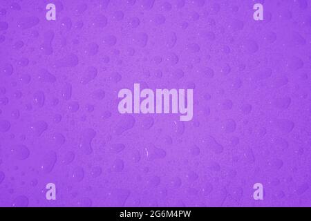 Top view of vibrant purple colored water droplets on the tabletop Stock Photo