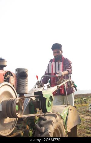 Indian Man using the power tiller to plough the fields Stock Photo