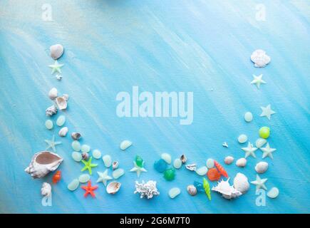 Seashells summer background. Many different seashells, starfish on a background of turquoise shimmering strokes. Creative flat lay banner, workspace c Stock Photo