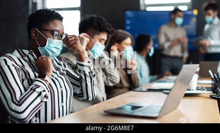 Multiracial people wearing medical masks using laptop Stock Photo