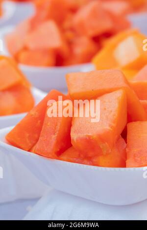 Slices of Papaya fruit - served on small white plates are a popular steet food of local people pf Kolkata. West Bengal - India. Vertical image Stock Photo