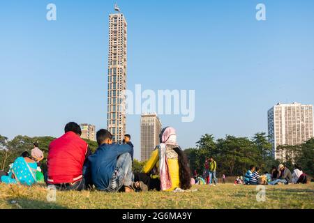 KOLKATA, WEST BENGAL, INDIA - DECEMBER 25TH 2017 : Family dressed in bright colours sitthing on grass and chatting at Kolkata maidan. It is a place fo Stock Photo