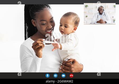 African American mother having video call with pediatrician using thermometer Stock Photo
