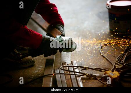 Welder used grinding stone on steel in factory with sparks, Welding process at the industrial workshop, hands with instrument in frame. Stock Photo