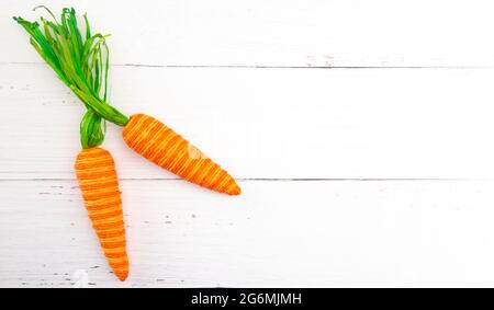 Two Decorative Carrots on a White Wooden Background Stock Photo