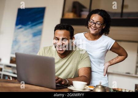 Middle eastern man and woman smiling while working with laptop at home Stock Photo