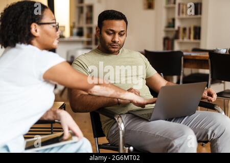 Middle eastern man and woman talking while working with laptop and tablet computer at home Stock Photo