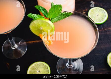 Pink Grapefruit Martinis with Garnish: Citrus martinis garnished with mint sprigs, lime slices, and pink grapefruit twists Stock Photo