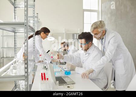 Young and senior adult male scientific researchers working in modern laboratory Stock Photo