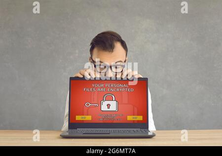 Man gets his laptop computer hacked and receives a ransomware warning on the screen Stock Photo