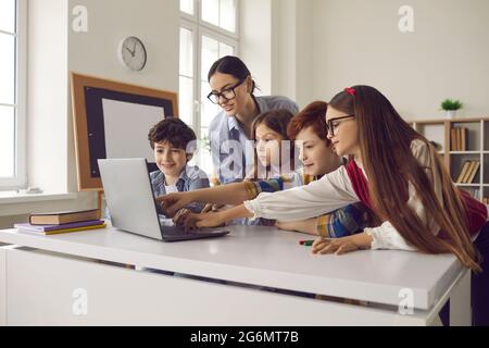 Pupil pointing at laptop screen discussing with teacher media material on lesson Stock Photo