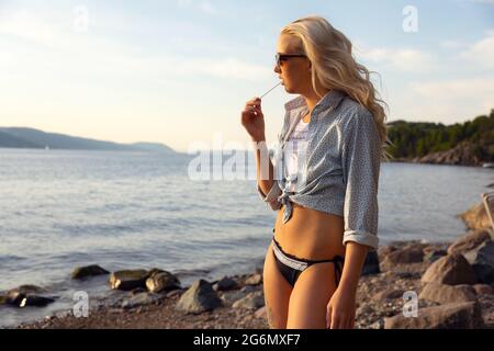 Beautiful Blonde Young Woman Eating Flavored Ice At Beach Stock Photo