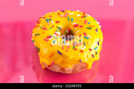 A Yellow Sprinkle Donut on a Pink Background Stock Photo
