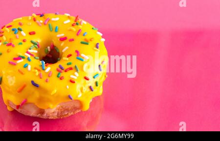 A Yellow Sprinkle Donut on a Pink Background Stock Photo