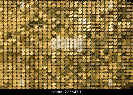 rows of blinking golden yellow brass metal plaques sway in wind and shines in sun and create unique pattern of movement. round reflective particles te Stock Photo