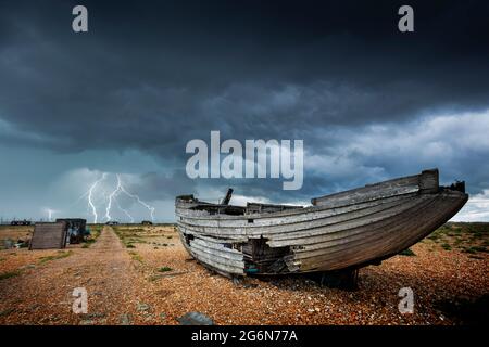 Wrecked boat in a storm on the shingle beach at Dungeness National Nature Reserve Kent England UK GB Europe Stock Photo