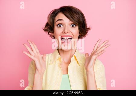 Photo of sweet impressed young woman wear yellow shirt rising arms isolated pink color background Stock Photo