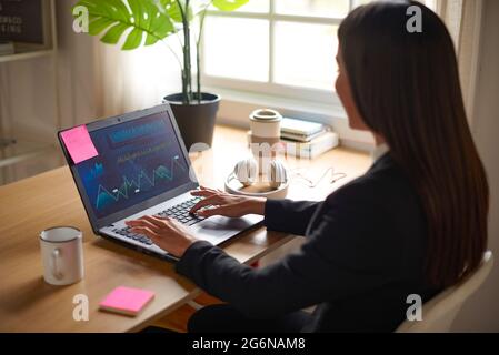 Young trader woman working on laptop computer inside modern office - Focus on screen Stock Photo