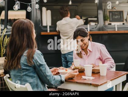 Mature women having fun eating at food truck outdoor - Focus on right face Stock Photo