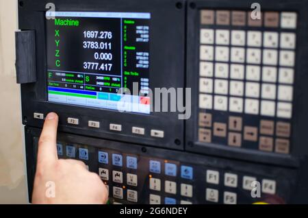 The process of programming a CNC machine. Entering data into a computer controlled machine, starting CNC engraving, control screen. Furniture manufact Stock Photo