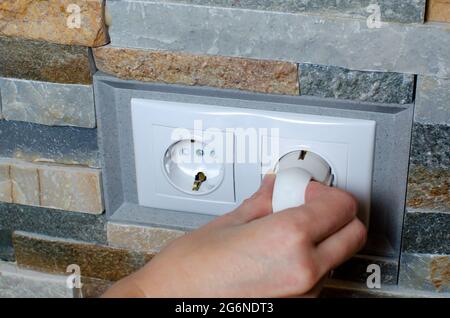 A socket with an electric plug in the wall. Energy saving concept Stock Photo