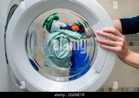 Woman loads the washing machine, washing sportswear. Washing Colorful Clothes Stock Photo