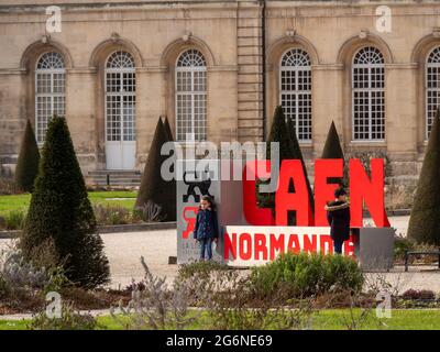 Caen, France, luty 2021. Saint Etienne Church, Caen, France. A stand with the inscription -Caen Normandy. A boy and a girl standing next to the childr Stock Photo