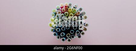 Drinking Straw. Colored paper cocktail tubes on a pink background. In a glass cup. View from the top, close-up. Space for text Stock Photo