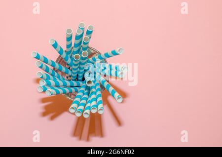 Drinking Straw. Colored paper cocktail tubes on a pink background. In a glass cup. View from the top, close-up. Space for text Stock Photo