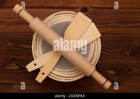 Antique traditional flour sieve, made from beech wood and fine wire mesh, dough rolling pin and culinary spatulas on a brown background. Set for sifti Stock Photo