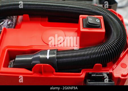 There is a black hose on the red industrial vacuum cleaner. Stock Photo