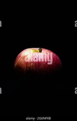 Dark low key image of a fresh and ripe red apple lit from above only Stock Photo
