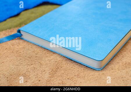 A paper diary in a blue leather cover with a bookmark. On pieces of multi-colored leather Stock Photo