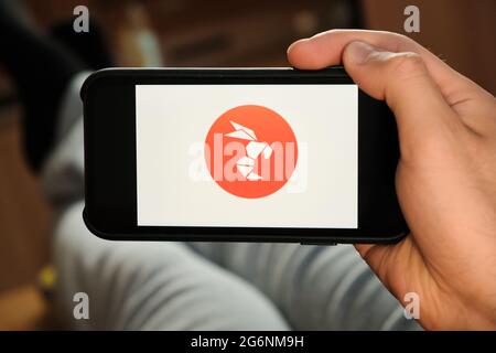 Hornet logo on the screen of smartphone in mans hand laying on the sofa. Application for dating, June 2021, San Francisco, USA Stock Photo