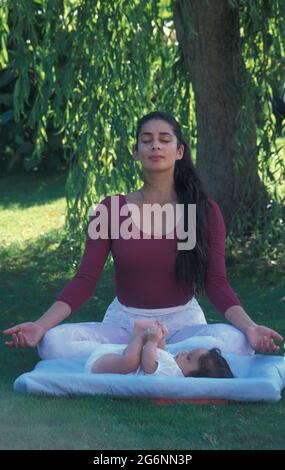 woman doing yoga outside with her newborn baby Stock Photo