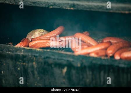 Polish Sausages being cooked and smoked on an outdoor grill at a festival Stock Photo