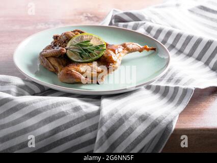 Roasted quail in a caramelised sauce with rosemary and lime on a plate. Chicken tobacco in rustic style for your meat menu on the lunch or dinner. Stock Photo