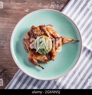 Grilled quail in a honey sauce in a plate on a wooden table background, flat lay. Stock Photo