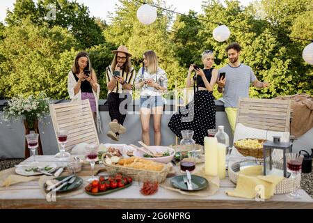 People spending time together, sitting separately in smart phones at party outdoors Stock Photo