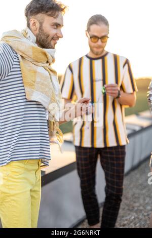 Young friends hang out at rooftop terrace on sunset Stock Photo