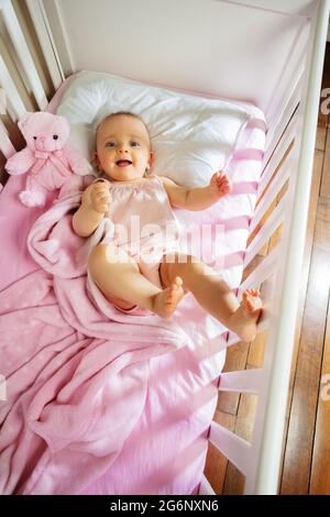 Baby girl lay in pink bed laughing and smiling Stock Photo