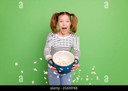 Photo of funky excited school girl wear white pullover cooking pop corn looking empty space isolated green color background Stock Photo