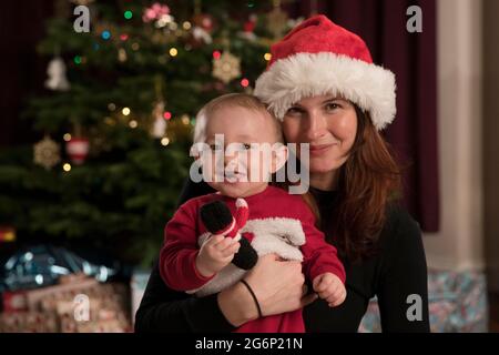 A mother and son posing in front of a Christmas tree Stock Photo