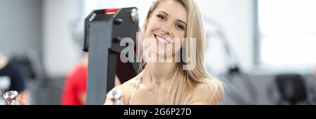 Sportive woman doing exercises for biceps on simulator Stock Photo